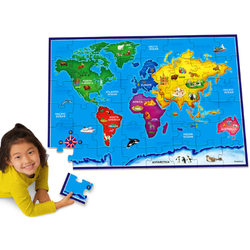 Child assembling a colorful world map floor puzzle featuring continents, oceans, and animals.